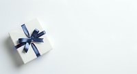 White gift box with navy blue ribbon bow on light background, isolated for holiday, celebration, and present design projects.