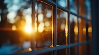 Dramatic sunset light creates golden bokeh through window panes, with teal and orange tones creating moody atmospheric scene. Shallow depth of field captures dreamy ambiance.