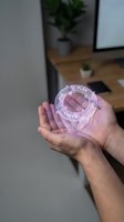 Close-up of male hands holding transparent holographic sphere with plan-do-check-act cycle diagram, office workspace background with potted plant and desk.