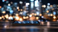 Modern smartphone on wooden table with glowing screen against blurred city lights bokeh background creating magical atmosphere at night.