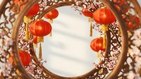 Traditional red lanterns hanging in ornate wooden circular frame with intricate carved patterns creating festive atmosphere for celebrations and cultural events.