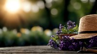 Rustic garden scene with straw hat and fresh purple wildflowers on wooden surface, soft sunset bokeh background creates dreamy summer atmosphere.