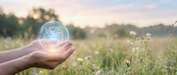 Hands holding glowing brain hologram in green meadow at sunset representing artificial intelligence, mental health, psychology and innovative thinking concepts.