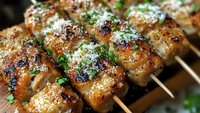 Grilled chicken skewers with herbs and parmesan cheese on wooden cutting board. Juicy barbecue meat kebabs with fresh parsley for summer cooking and dining.