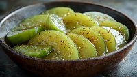 Fresh sliced green apples arranged in wooden bowl with sesame seeds and honey glaze for healthy snacking and culinary presentations.