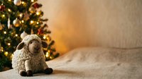 Stuffed sheep toy sitting on carpet with decorated evergreen tree and warm golden lights in background during festive season.