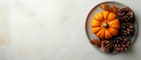 Orange pumpkin and pine cones on rustic ceramic plate against light marble background, flat lay composition with copy space for seasonal design.