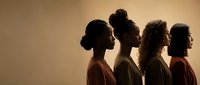 Silhouettes of four diverse women in profile against warm golden background showcasing unity, sisterhood and female empowerment in artistic lighting.