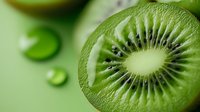 Fresh juicy kiwi slice macro with water drops on green background showing detailed texture, seeds and flesh pattern, healthy tropical fruit concept.