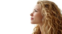 Profile view of young Caucasian woman with long wavy blonde hair looking up thoughtfully against white background, isolated portrait suitable for beauty and haircare advertising.