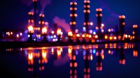 Blurred city lights reflecting on calm water surface at night with vibrant purple and orange bokeh effect creating dreamy urban landscape atmosphere.