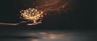 Hand holding glowing magical light particles with sparkling effects against dark background for fantasy and inspiration concepts.