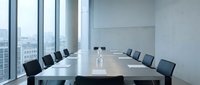 Modern conference room with long table, black chairs, and floor-to-ceiling windows overlooking cityscape. Suitable for corporate meetings, business presentations, and office environments.