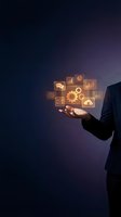 Businessman in suit holding glowing digital icons with gears, charts, and cloud symbols, representing technology and business management.