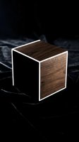 Modern wooden cube with white frame edges on dark marble surface, showcasing minimalist design and contemporary furniture styling for interior decoration and product visualization.
