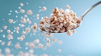Floating popcorn on spoon against blue background with scattered kernels creating dynamic motion effect, food levitation photography for snack advertising.