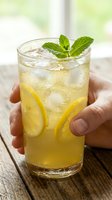 Refreshing lemonade with fresh mint garnish and lemon slices held in hands on rustic wooden table for summer beverage and restaurant menu concepts.