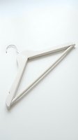 White wooden clothes hanger with metal hook on light background, wardrobe organization concept for fashion, retail, and home storage design.