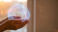 Hand holding glowing orb of light against warm window backdrop, symbolizing hope, energy, innovation, and future possibilities for business and technology concepts.
