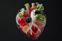 Creative anatomical heart made from fresh fruits and vegetables in glass container against black background, showcasing healthy eating concept.