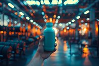 Hand holding trendy reusable turquoise water bottle in modern gym interior with atmospheric bokeh lighting, perfect for fitness, wellness and healthy lifestyle marketing campaigns.