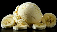 Creamy vanilla ice cream scoop with fresh sliced banana pieces arranged on dark background, creating contrast between cold dessert and tropical fruit flavors.