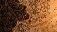 Ornate carved wooden surface with intricate floral patterns and decorative motifs showcasing traditional craftsmanship and artistic detail on textured material.