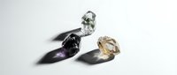 Three sparkling cut gemstones with dramatic shadows on white background. Luxury jewelry stones including clear, dark and golden crystals for elegant design.