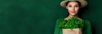 Young woman in green outfit holding fresh lettuce against emerald background for healthy eating and organic food concepts.