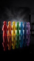 Seven colorful human figures holding hands in rainbow colors representing diversity, unity and teamwork with dramatic lighting and reflections.