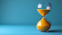 Hourglass with flowing golden sand against turquoise background, measuring time passage in dramatic lighting with copy space for business concepts.