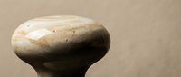 Smooth polished stone with natural marble-like patterns and earth tones against neutral background for spa wellness meditation decor applications.
