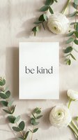 Be kind motivational card surrounded by white ranunculus flowers and eucalyptus on a soft linen background, flat lay style for social media.