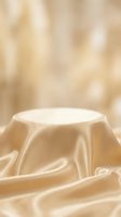Luxury gold satin draped podium on silky fabric background for elegant product display and cosmetic presentation.