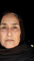 Middle-aged woman of Middle Eastern or South Asian descent wearing black headscarf against dark background. Mature female portrait for healthcare, aging, diversity, and cultural representation projects.