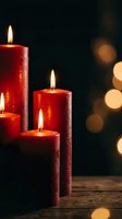 Red candles burning with warm flames on wooden surface creating cozy atmosphere with golden bokeh lights in dark background for holiday decoration.
