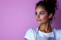 Young mixed race woman with messy bun hairstyle wearing white apron and t-shirt looking away with confident smile against purple background. Professional portrait.