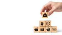 Hand placing wooden cube with email icon on pyramid of business symbol blocks on white background for corporate communication concept.