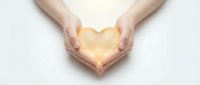 Hands gently cupping glowing golden heart shape against white background symbolizing love, care, protection, compassion and emotional wellness concept.