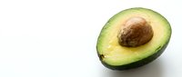 Halved avocado with pit on white background, fresh organic fruit for healthy eating, cooking, nutrition, and food photography projects.