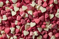 Small pink and white heart-shaped sugar candies creating romantic pattern background, sweet confectionery texture for Valentine's Day and love themes.