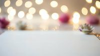 Festive holiday background with warm bokeh lights and decorative elements on white surface for seasonal greeting cards and winter celebrations.