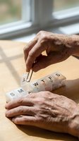 Senior hands organizing weekly pill dispenser on wooden table by window for medication management and healthcare routine.
