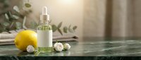 Lemon essential oil in dropper bottle with fresh citrus fruit and chamomile flowers on marble surface for skincare and wellness products.