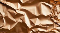 Crumpled metallic rose gold foil texture with dramatic shadows and highlights creating abstract geometric patterns and folds for luxury backgrounds.