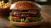 Gourmet burger with sesame seed bun, beef patty, melted cheese, fresh lettuce, tomato and red onion slices served with fries for restaurant menus and food advertising.