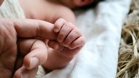 Newborn baby tiny hand grasping adult finger, close-up shot capturing tender parent-child bond, soft natural light, warm family moment.