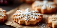 Freshly baked gingerbread cookies with snowflake patterns dusted with powdered sugar on parchment paper for holiday baking and festive celebrations.