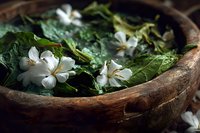 Fresh jasmine flowers and green leaves in rustic wooden bowl, creating aromatic spa composition for natural cosmetics and aromatherapy treatments.