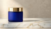 Luxury blue glass cosmetic jar with golden lid on marble surface for premium skincare product packaging and beauty brand marketing campaigns.